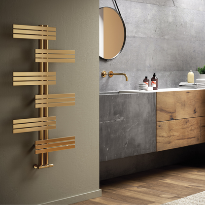The Babyla gold-toned stainless steel hot water towel warmer mounted on a wall with multiple horizontal bars, positioned in a bathroom setting.