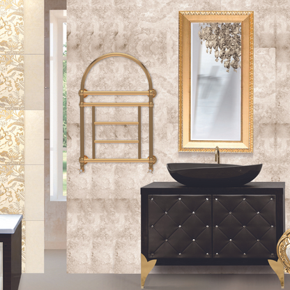 Elegant retro-style hot water towel warmer with a curved top rail, in an antique gold finish, mounted on a wall beside a black vanity with gold accents.
