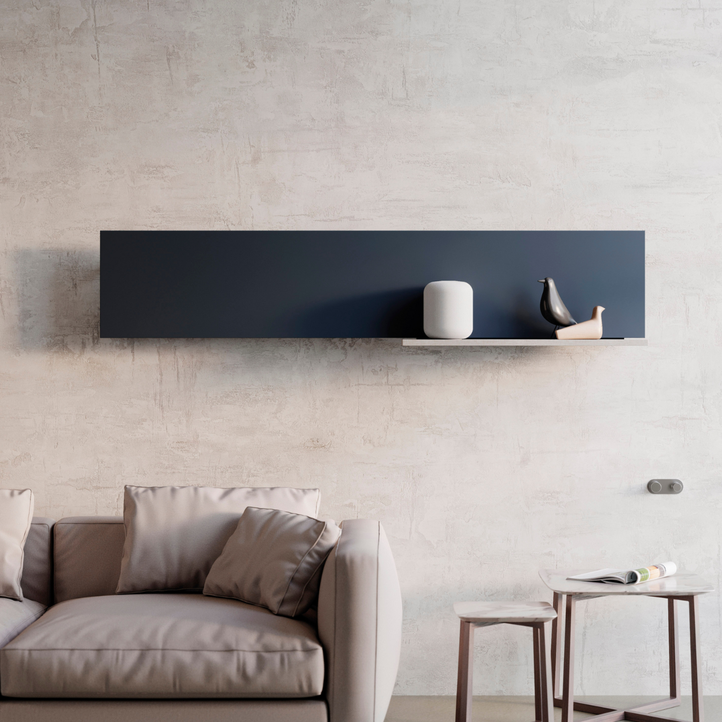 A horizontal hot water radiator with a sleek black frame mounted on a wall above a grey sofa and a small round side table.