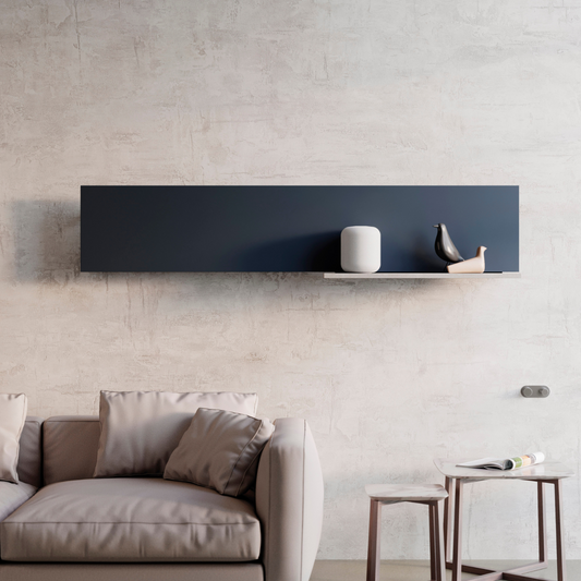 A horizontal hot water radiator with a sleek black frame mounted on a wall above a grey sofa and a small round side table.