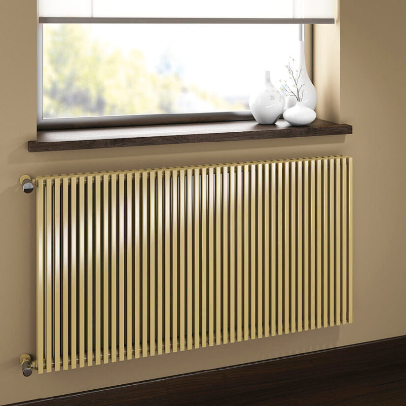 Beige radiator on a wall with a window and room interior in the background